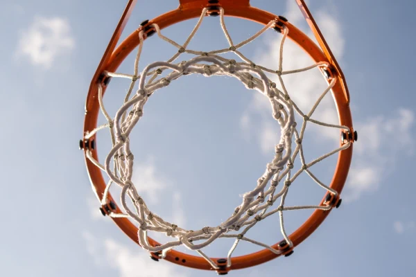 Ein Basketballkorb vor einem klaren Himmel, mit weichem Licht, der den Korb und das Netz zeigt.